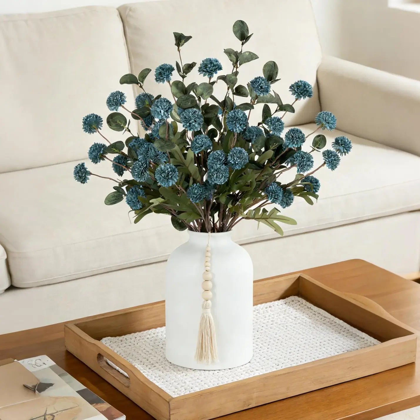 Blue artificial flowers styled in vase on coffee table